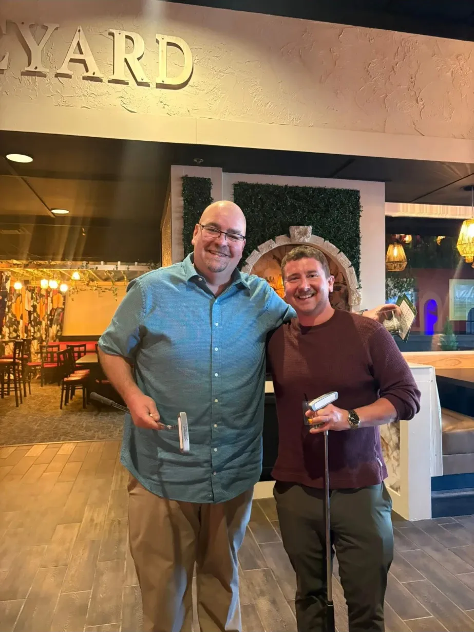 Tony Paumier with Bistro founder Roger Stewart, both holding putters
